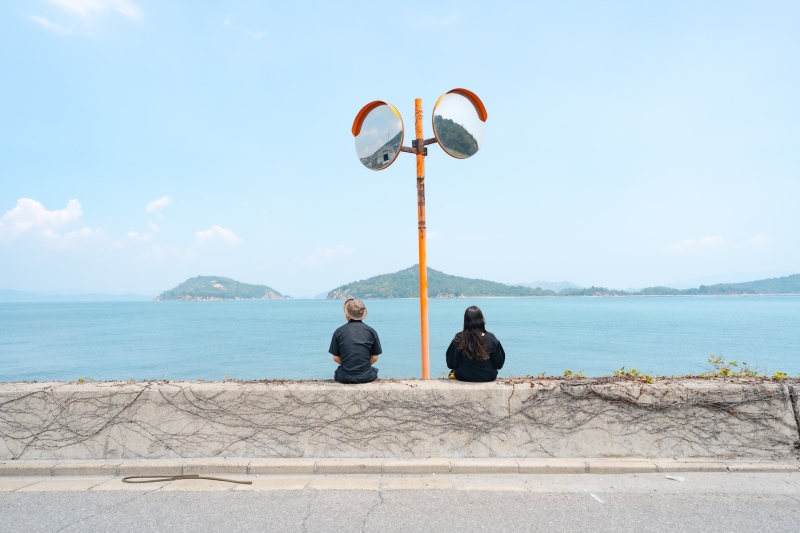 夏の海で旅行をしている写真。海辺に佇む二人