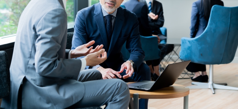 ビルの窓際に座り話す複数のかっこいいビジネスマン